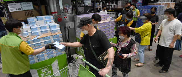 지난 7일 경기도 하남시 이마트 트레이더스에서 고객들이 쌓여 있는 마스크를 마스크를 구입하고 있다./권욱기자
