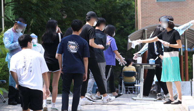 8일 서울 중랑구 원묵고등학교에 마련된 임시 선별진료소에서 이 학교 학생들이 신종 코로나 바이러스 감염증(코로나19) 검사를 받기 전 학교에 도착해 비닐장갑을 받은 뒤 차례를 기다리고 있다. /연합뉴스