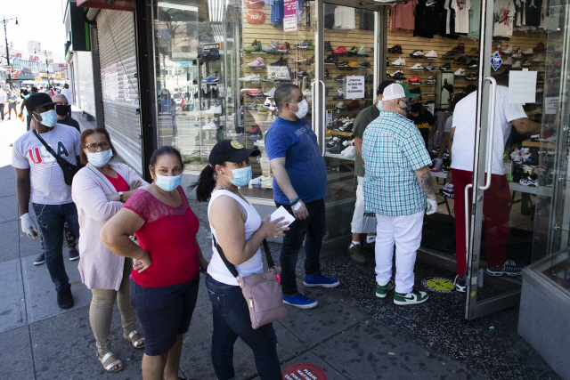 미국에서 코로나19 피해가 가장 컸던 뉴욕시가 1단계 경제 정상화 조치에 들어간 8일(현지시간) 브롱크스 자치구에서 재개장한 신발 매장 앞에 마스크를 착용한 고객들이 줄지어 입장을 기다리고 있다.  /AP연합뉴스