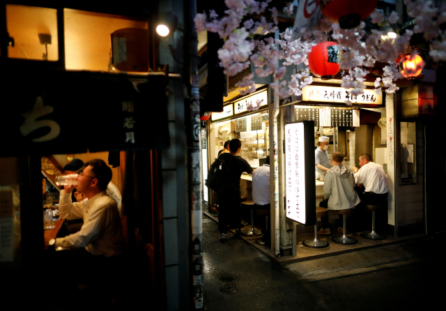 지난달 26일 일본 도쿄 신주쿠 거리에 모인 사람들이 이자카야에서 저녁을 먹으며 술을 마시고 있다. /로이터연합뉴스