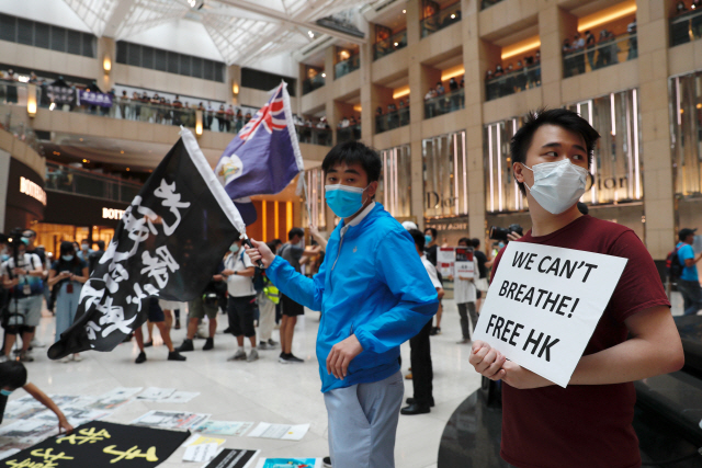 범죄인인도법안(송환법) 반대시위 1주년인 9일(현지시간) 홍콩 시내의 한 쇼핑몰에서 시민들이 ‘우리도 숨을 쉴 수 없다. 홍콩을 자유롭게 하라’고 적힌 팻말과 홍콩 민주화 촉구 구호가 담긴 깃발 등을 들고 시위를 벌이고 있다./로이터연합뉴스