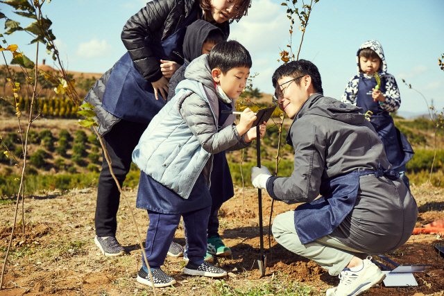 한화 ‘태양의 숲’ 원정대가 2018년 ‘7호 태양의 숲’ 조성 행사에서 묘목을 심고 메시지를 남기고 있다. /사진제공=한화