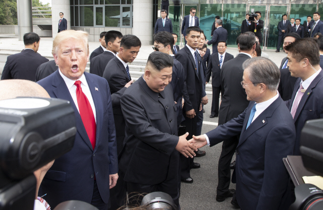 지난 해 6월 30일 문재인 대통령과 북한 김정은 국무위원장이 판문점 남측 자유의 집 앞에서 만나 악수하고 있다. 왼쪽은 트럼프 미국 대통령./연합뉴스