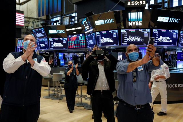 지난달 22일(현지시간) 코로나19 확산방지 조치로 인해 문을 닫았던 미국 뉴욕증권거래소(NYSE)의 재개장을 앞두고 직원들이 축하하고 있다. /로이터연합뉴스