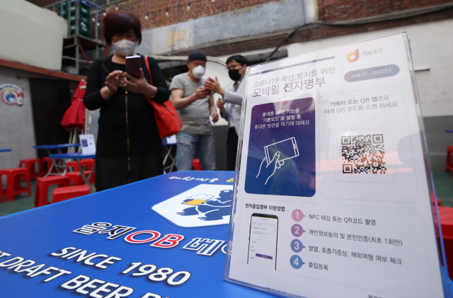 서울 중구 을지로 노가리 골목에서 구청 직원들이 상인들을 대상으로 QR코드 교육을 하고 있다.  /연합뉴스