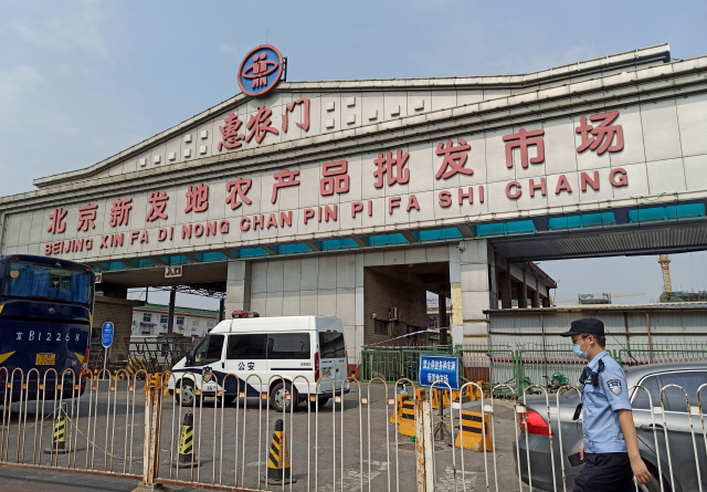 코로나19 확진자 발생으로 베이징 최대 농산물시장인 신파디시장이 폐쇄된 가운데 중국 공안이 13일 시장 입구를 막은 채 경비를 서고 있다./AFP연합뉴스