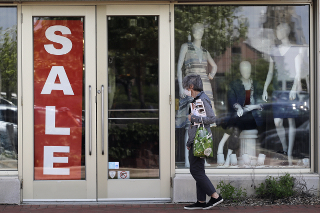 11일(현지시간) 미국 일리노이주 디어필드에 ‘할인’을 써붙인 한 매장 앞을 마스크를 착용한 여성이 지나가고 있다. /AP연합뉴스