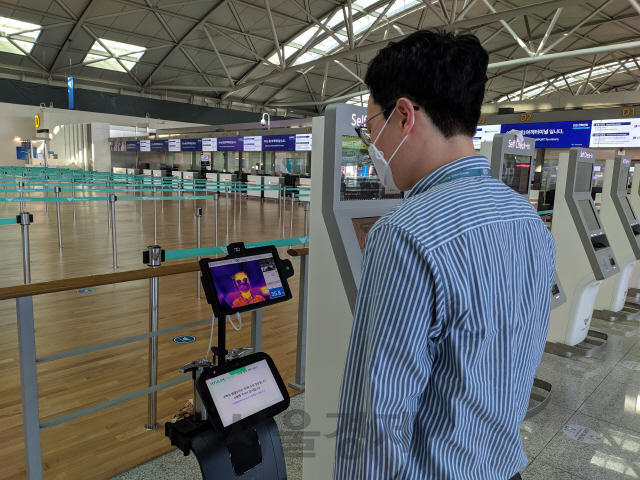 15일 인천공항 1여객터미널에서 한 승객이 발열체크 로봇앞에 서서 체온을 측정하고 있다./사진=인천공항공사