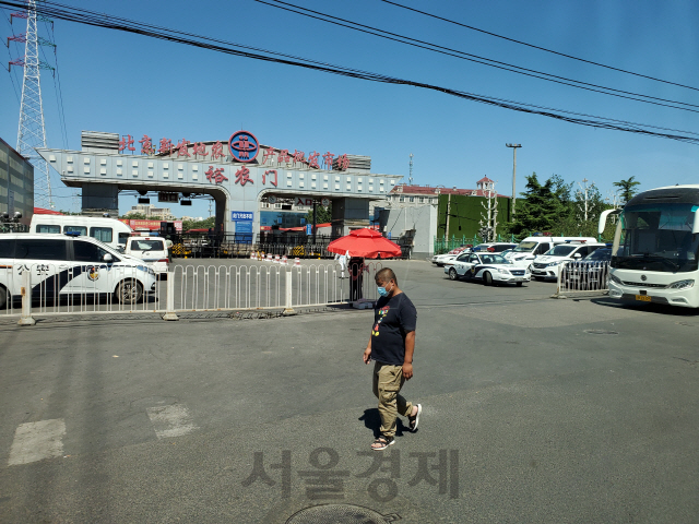 중국 베이징이 최대 농산물도배시장인 신파디시장이 13일부터 전면 폐쇄된 가운데 14일 한 시민이 문이 닫힌 출입구 앞을 지나가고 있다. /최수문기자