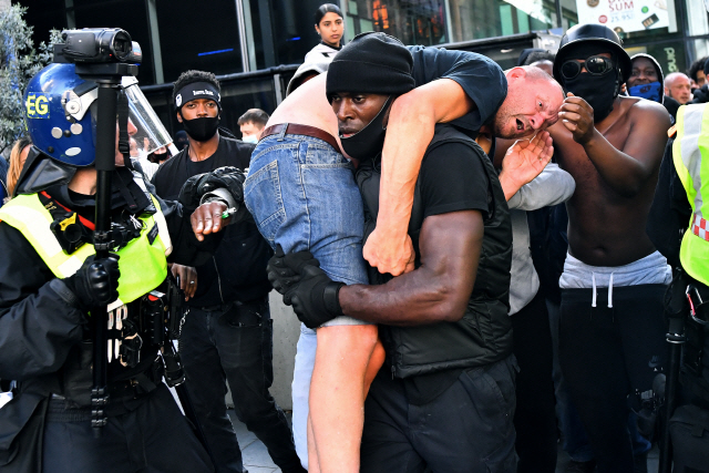 인종차별 항의 시위를 하던 패트릭 허치슨이 영국 런던 워털루역 부근에서 부상당한 백인 남성을 안전한 장소로 옮기고 있다. /런던=로이터연합뉴스