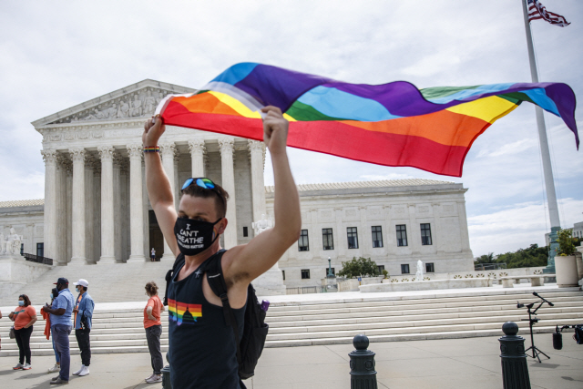 15일(현지시간) 한 LGBTQ 지지자가 미국 워싱턴DC 대법원 앞에서 이들을 상징하는 깃발을 들고 있다. 이날 미 대법원은 성적 성향을 이유로 한 고용차별이 위법이라고 판결했다. /EPA연합뉴스