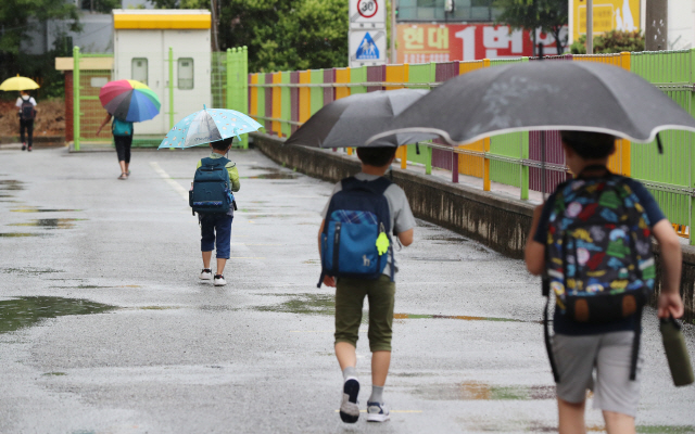 광주·전남지역에 비가 내린 18일 오전 광주 북구 오치초등학교에서 학생들과 병설유치원생들이 마스크를 쓰고 코로나19 예방 발열체크를 하기 위해 줄지어 이동하고 있다./광주=연합뉴스