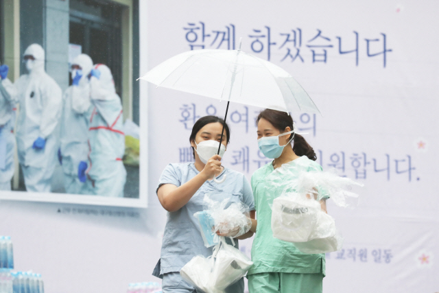 지난 10일 오전 대구시 신종 코로나바이러스 감염증(코로나19) 지역거점병원인 계명대학교 대구동산병원에서 간호사들이 우산을 쓰고 보호구 착의실로 향하고 있다. /연합뉴스