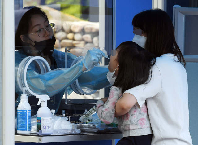 지난달 31일 서울 영등포구 여의도 자매근린공원에 마련된 코로나19 워킹스루 선별진료소를 찾은 한 어린이가 엄마의 도움으로 코로나19 검사를 받고 있다. /오승현기자