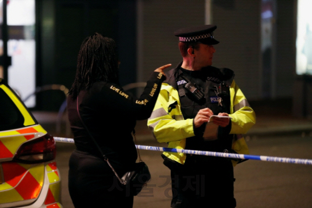 20일(현지시간) 영국 리딩 도심에서 무차별 흉기 공격이 발생한 후 경찰관이 한 시민에게 증언을 듣고 있다. /리딩｜로이터연합뉴스