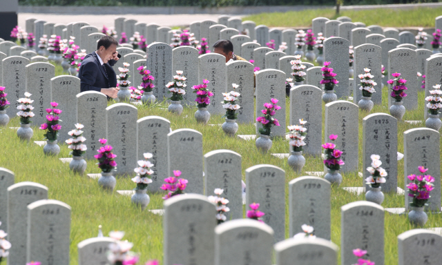 지난 21일 서울 동작구 국립서울현충원에서 6.25 전사자 유족들이 묘비 앞에서 고인을 생각하고 있다./연합뉴스