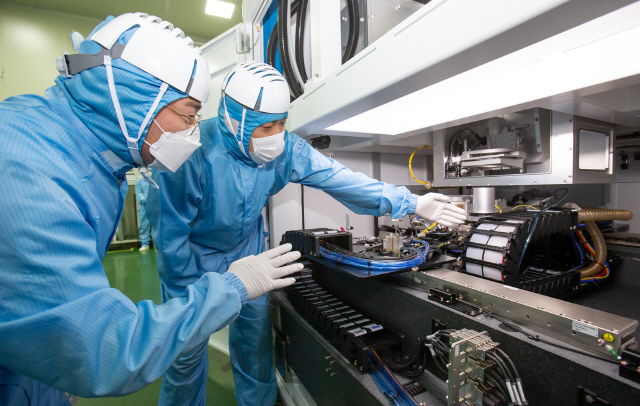삼성전자 직원(왼쪽)과 이오테크닉스 직원이 양사가 공동 개발한 반도체 레이저 설비를 함께 살펴보고 있다. /사진제공=삼성전자