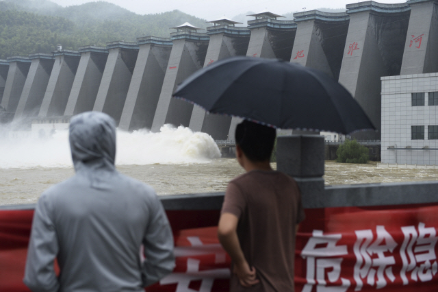 지난 23일(현지시간) 중국 안후이성 훠산현 주민들이 포쯔링 댐 앞에서 폭우로 불어난 물이 방류되고 있는 모습을 지켜보고 있다./신화연합뉴스