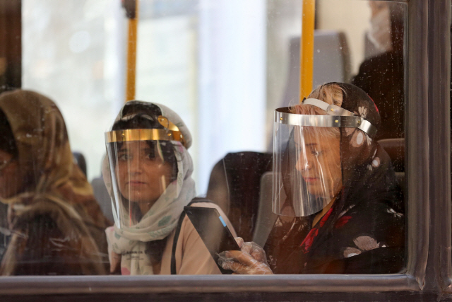 지난 22일(현지시간) 이란 테헤란의 한 버스 안에서 코로나19 전염을 방지하기 위해 안면보호대를 착용한 승객들이 앉아 있다. /AFP연합뉴스
