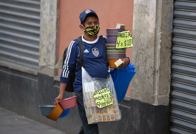 21일(현지시간) 멕시코의 멕시코시티에서 마스크를 쓴 상인이 물건을 판매하고 있다./멕시코시티=AFP연합뉴스