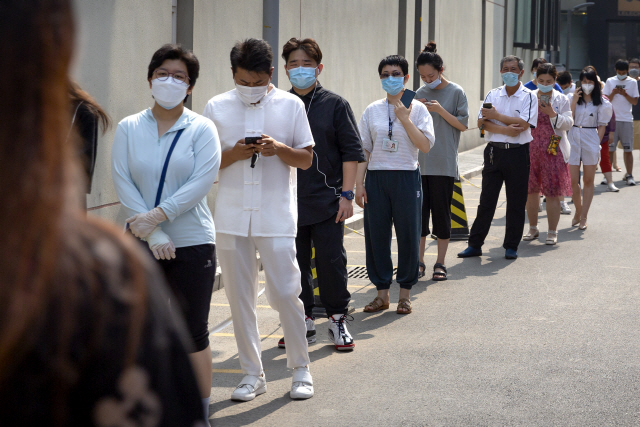 중국 수도 베이징에서 코로나19 집단감염이 지속되는 가운데 28일 한 지역 보건소에서 마스크를 착용한 시민들이 줄지어 검사 순서를 기다리고 있다. /AP연합뉴스