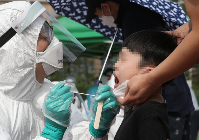 지난 2일 대전시 동구 천동 천동초교에서 한 학생이 입을 크게 벌리고 검체 채취를 받고 있다. /연합뉴스