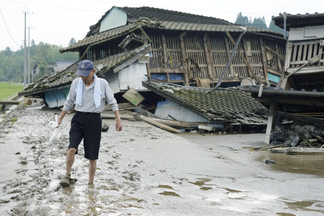 5일 일본 구마모토현에서 한 남성이 폭우로 피해를 당한 집을 뒤로한 채 진흙투성이 길을 걷고 있다./AP연합뉴스