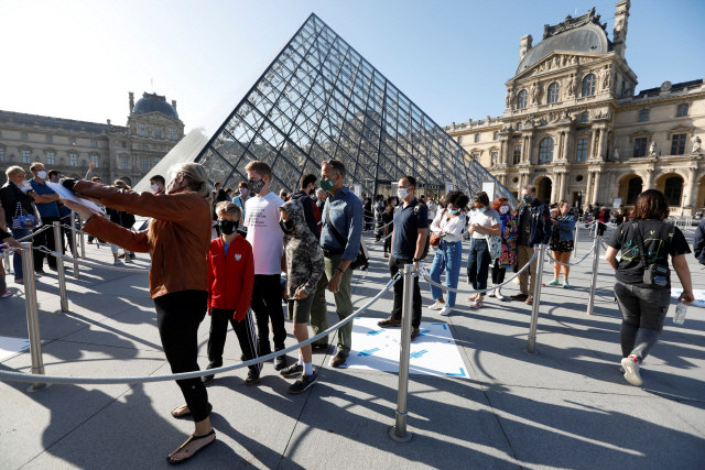 연간 960만명의 관광객이 찾는 프랑스 파리 루브르박물관이 코로나19로 폐쇄된 지 4개월 만에 재개장하는 6일(현지시간) 박물관 입구인 유리 피라미드 앞에 관람객들이 입장을 위해 줄을 서 있다./로이터연합뉴스