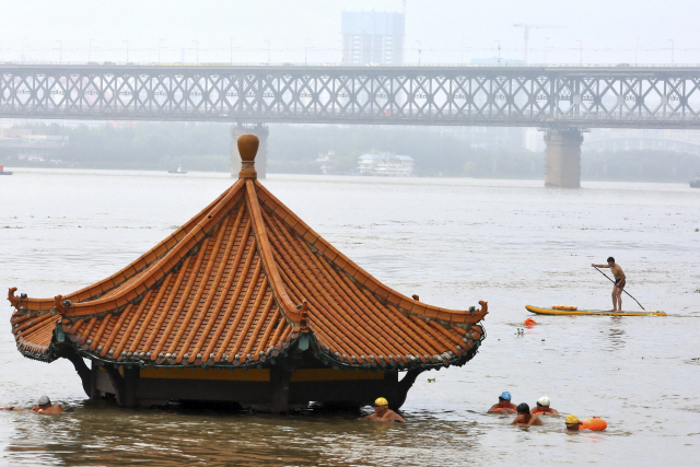 중국 남부 지역에 한 달 넘게 폭우가 쏟아지면서 인명 피해가 잇따르는 가운데 8일 중국 후베이성 우한의 주민들이 창장(長江·양쯔강)이 범람하면서 물에 잠긴 정자 옆을 헤엄쳐 이동하고 있다./AP연합뉴스