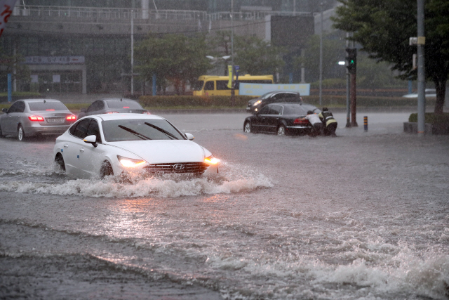 10일 물바다로 변한 부산 해운대구 센텀시티 근처 도로를 한 승용차가 어렵게 지나고 있다. 부산 일대는 폭우가 쏟아지면서 이날 호우경보가 발효됐다. /부산=연합뉴스