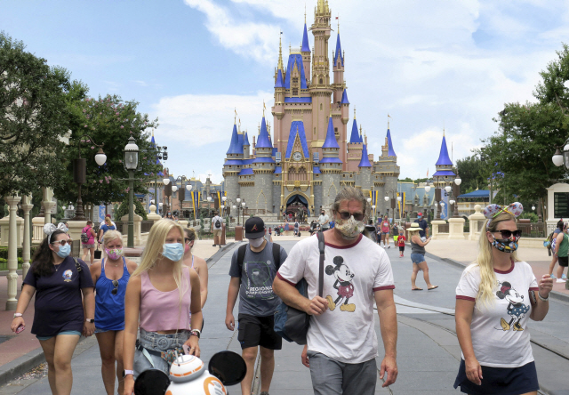 신종 코로나바이러스 감염증(코로나19) 확산으로 폐쇄됐던 미국 플로리다주 올랜도 디즈니랜드가 부분적으로 재개장한 11일(현지시간) 관광객들이 마스크를 착용한 채 걷고 있다./AP연합뉴스