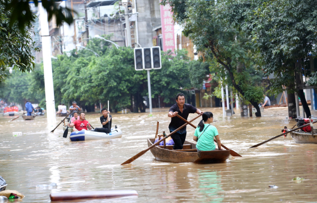 중국 남부에서 한 달 이상 홍수가 이어지는 가운데 11일(현지시간) 광시성 롱수이의 침수지역에서 시민들이 배를 타고 이동하고 있다./신화연합뉴스