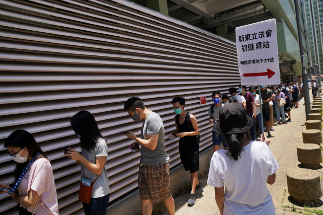 12일 홍콩에서 열린 예비선거에 참석하기 위한 시민들이 마스크를 착용한 채 줄을 서 있다./로이터연합뉴스