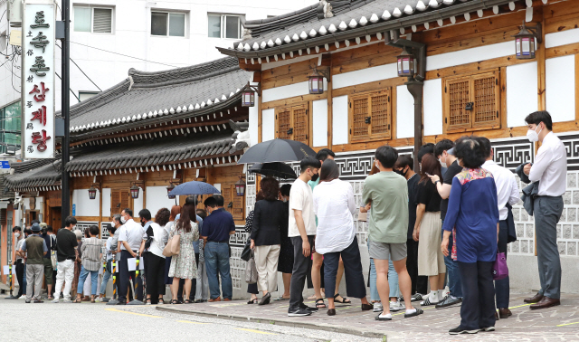 초복인 16일 30도 안팎의 찜통더위가 이어진 가운데 서울 종로구의 한 삼계탕 전문점 앞에 손님들이 길게 줄지어 서 있다. /연합뉴스