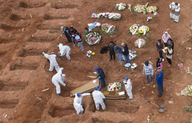 지난 15일(현지시간) 브라질 상파울루의 공동묘지 빌라포르모사에서 보호복을 착용한 관계자들이 코로나19 사망자가 담긴 관을 묻고 있다./AP연합뉴스
