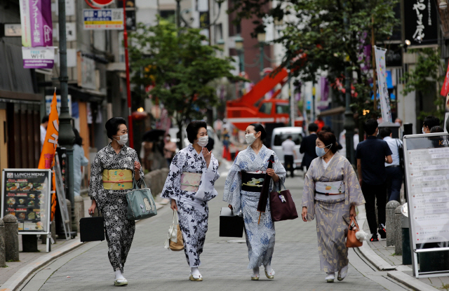 마스크를 쓴 일본 게이샤들이 지난 13일 도쿄 시내를 걸어가고 있다./로이터연합뉴스