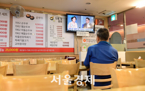 신종 코로나 바이러스 감염증 사태로 경기가 위축돼 손님이 없는 한 음식점에서 사장이 홀로 TV를 보고 있다.