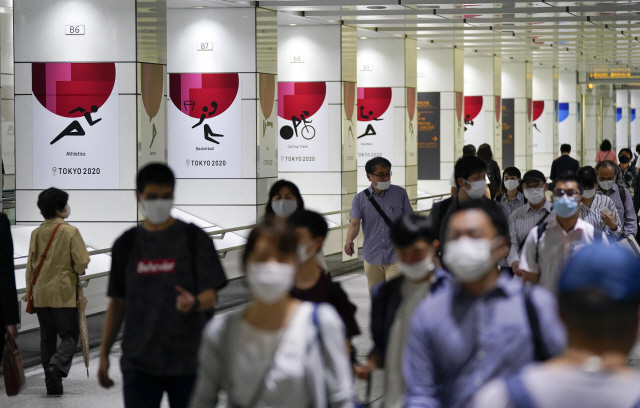 15일 일본 도쿄에서 마스크를 착용한 사람들이 길을 도쿄 2020올림픽 포스터 앞을 지나가고 있다. /EPA연합뉴스