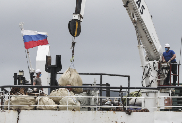 러시아 원양어선 페트르원호(7,733t)에서 마스크를 쓴 선원들이 작업하고 있다. 이 선박 선원 94명 중 32명이 코로나19 확진 판정을 받았다./연합뉴스