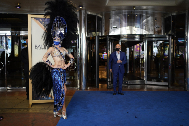 23일(현지시간) 미국 라스베이거스의 호텔 재개장을 맞아 쇼걸이 마스크를 착용한 채 문 앞에 서 있다. /AP연합뉴스