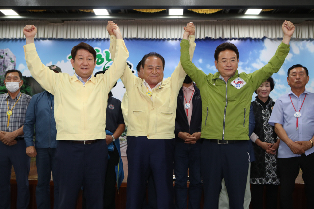 30일 오후 경북 군위군청에서 권영진 대구시장(왼쪽부터), 김영만 군위군수, 이철우 경북지사가 대구통합 신공항 이전지를 공동후보지로 신청할 것을 조건부 합의 후 손을 맞잡고 있다. /군위=연합뉴스