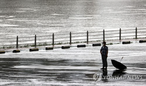 많은 양의 비가 내리는 2일 오후 서울 송파구 봉은교 아래 탄천주차장에서 한 시민이 잠시 비를 피하고 있다./연합뉴스