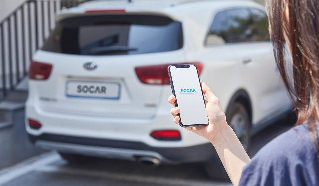 쏘카 모델이 해당 서비스 앱으로 카셰어링 차량을 호출하는 모습을 시연하고 있다. /사진제공=쏘카