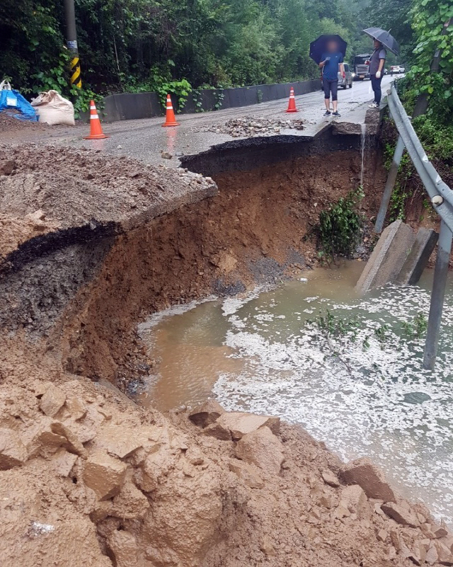 3일 오후 충북 제천시 금성면에서 시 관계자들이 폭우로 인해 유실된 도로를 살펴보고 있다. /연합뉴스