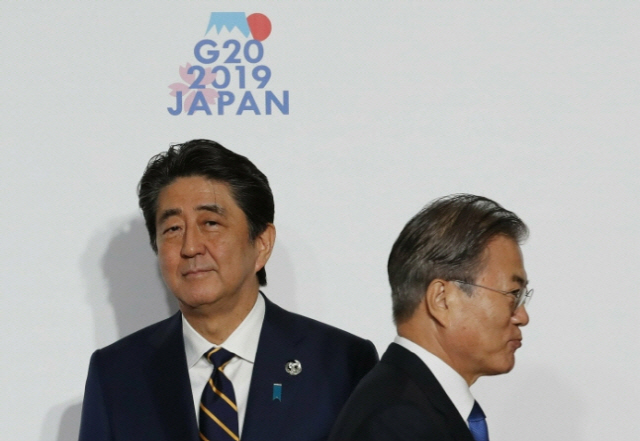 지난해 6월28일 일본 오사카에서 열린 주요 20개국(G20) 정상회의에서 문재인 대통령이 아베 신조 일본 총리와 악수한 뒤 지나가고 있다. /AP=연합뉴스