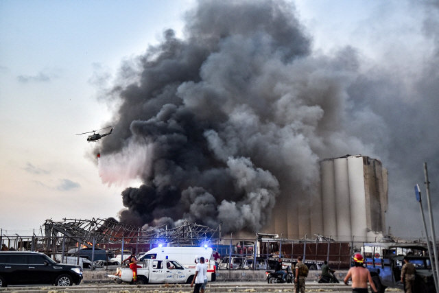 4일(현지시간) 레바논 수도 베이루트 항구의 대규모 폭발 현장에서 검은 연기가 피어오르는 가운데 소방헬기가 진화 작업을 벌이고 있다. /AFP연합뉴스