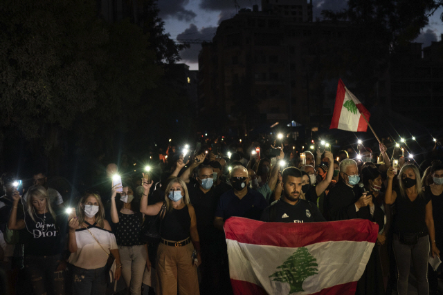 레바논 반(反)정부 시위대가 9일(현지시간) 플래시라이트가 켜진 휴대폰과 레바논 국기를 들고 베이루트 폭발 참사 피해자들을 추모하고 있다./AP연합뉴스