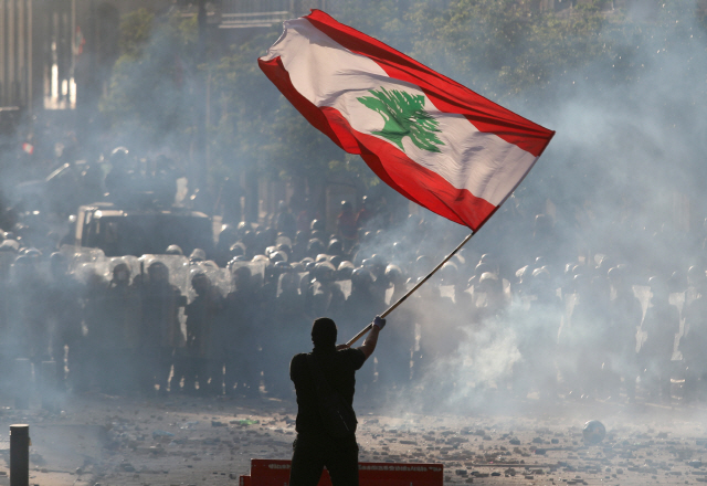 지난 4일(현지시간) 대규모 폭발 참사가 발생한 레바논 수도 베이루트에서 8일 반정부 시위 참가자가 레바논 국기를 흔들며 경찰과 대치하고 있다. /로이터연합뉴스