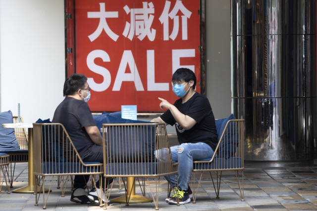중국이 소비촉진을 통한 경제정상화에 박차를 가하고 있는 가운데 베이징 시내 한 가게에서 사람들이 마스크를 쓴채 대화하고 있다. /AP연합뉴스