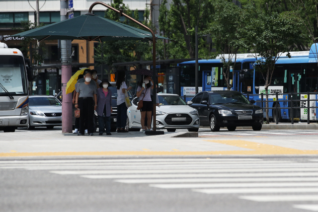 서울지역에 폭염경보가 내려진 17일 오후 세종대로 사거리 그늘막 아래에서 시민들이 신호를 기다리고 있다./연합뉴스